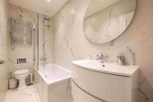 a white bathroom with a sink and a mirror at Cosy and Stylish Chelsea 2 bedroom flat in London