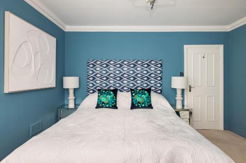 a blue bedroom with a large bed with two pillows at Cosy and Stylish Chelsea 2 bedroom flat in London
