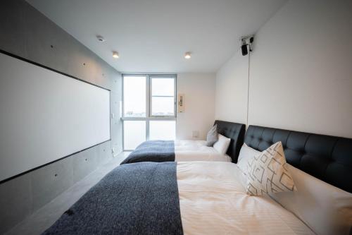 Un dormitorio con dos camas y una pantalla de proyección. en Minn Haneda Airport, en Tokio
