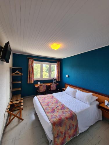 a bedroom with a large bed and a blue wall at Logis Hotel Eden Lac in Savines
