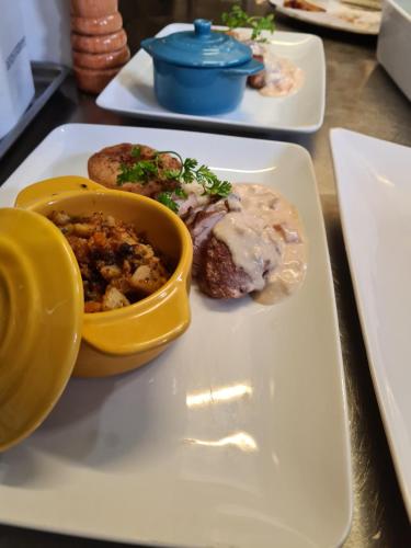 a white plate with a bowl of food on a table at Logis Hotel Eden Lac in Savines