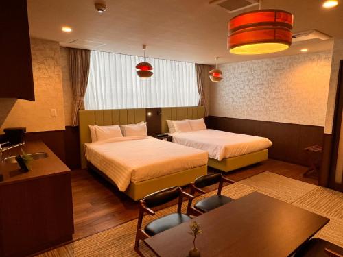 a hotel room with two beds and a table and chairs at KOUBOUNOYU HONTEN in Shizuoka