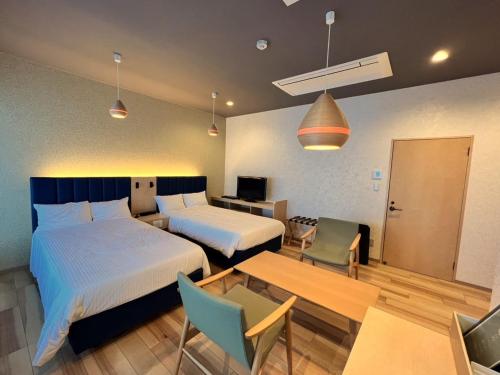 a hotel room with two beds and a table and chairs at KOUBOUNOYU HONTEN in Shizuoka