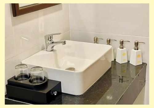 lavabo blanco en el baño con 2 botellas en Aurora Hotel Măng Đen, en Kon Von Kla