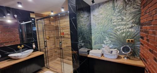 La salle de bains est pourvue d'une douche en verre et d'un lavabo. dans l'établissement Apartament " La Dolce Vita ", à Bryzgiel