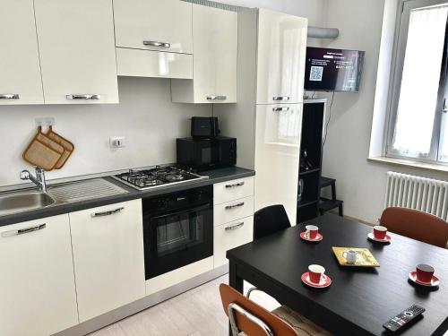 a kitchen with white cabinets and a table with cups on it at Rivis Apartament - center of Udine in Udine