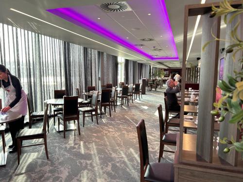 uma sala de jantar com mesas e cadeiras e iluminação roxa em Tynecastle Park Hotel em Edinburgo