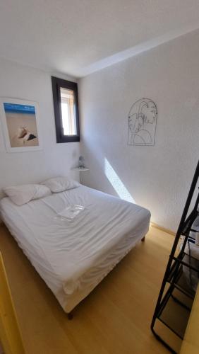 ein weißes Bett in einem Zimmer mit Fenster in der Unterkunft Gruissan-Port-T2-2chambres-5pers-43m2-climatisé-Parking-ValFred in Gruissan