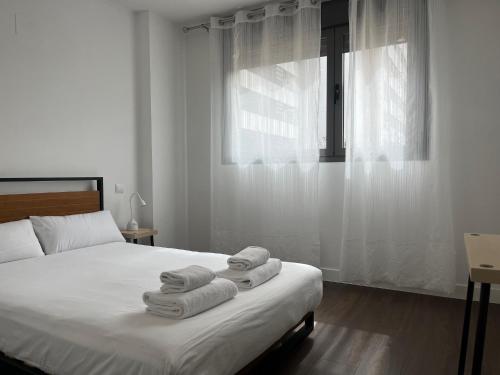 1 dormitorio con 1 cama con toallas en Valdebebas con piscina, gimnasio y garaje, en Madrid