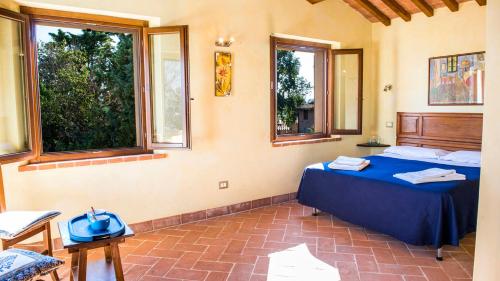 a bedroom with a blue bed and two windows at LA TORRE DEI FAGIANI 8&2 Emma Villas in Castiglione del Lago