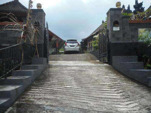 a car driving down a wooden path with a fence at Kadek Homestay in Besakih