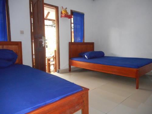a bedroom with two beds with blue sheets at Kadek Homestay in Besakih