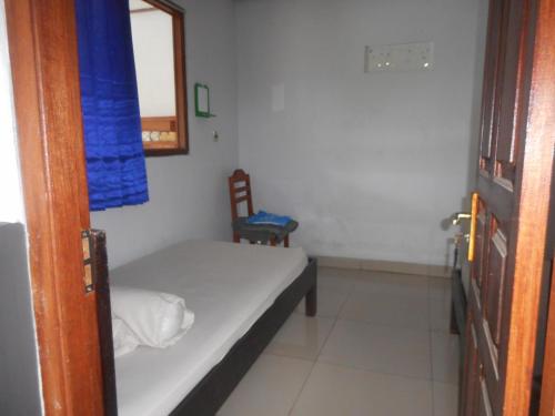 a small bedroom with a bed and a chair at Kadek Homestay in Besakih