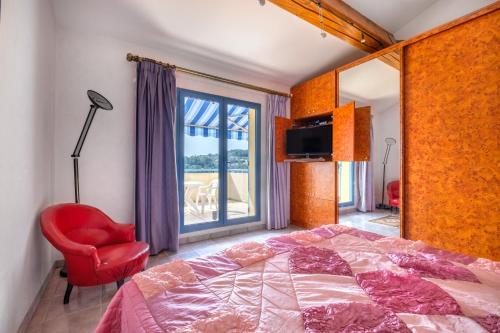 een slaapkamer met een bed, een rode stoel en een raam bij Numéro 2 in Valbonne