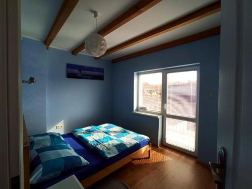 a blue bedroom with a bed and a window at Kostek in Rowy