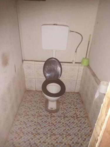 a small bathroom with a toilet with a black seat at Lusis Homestay in Lautoka