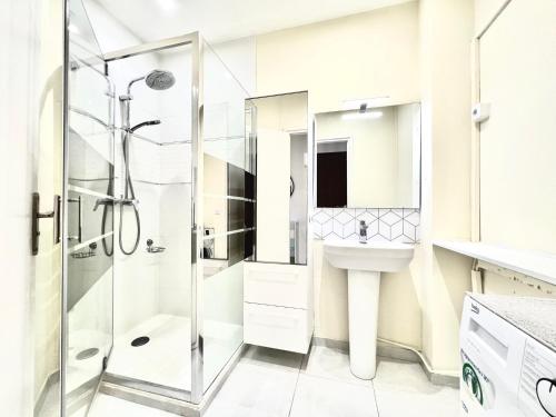 une salle de bain blanche avec une douche et un lavabo dans l'établissement ApartHotel Riviera - Terrasse des Bougainvillees - 100m Promenade des Anglais, à Nice