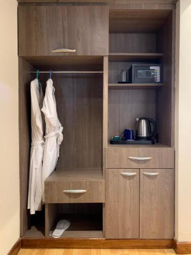 a closet with wooden cabinets and a microwave at Hotel Flower in Kathmandu