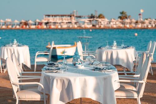 a group of tables and chairs with white table cloths on the beach at Labranda Royal Makadi in Hurghada
