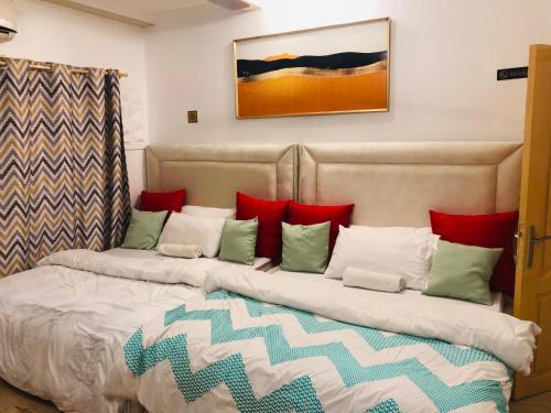 a bed with red and green pillows on it at Apartment in Dar es salaam, Palm Village in Dar es Salaam