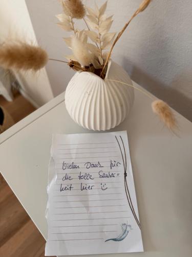 a vase sitting on a table with a piece of paper at Altstadtferienwohnung Stade-Cozy Home -ein zweites Zuhause finden in Stade