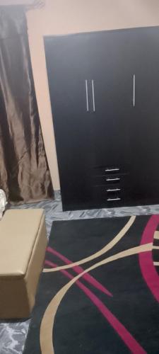 una camera con un tappeto nero e rosa e una scatola di G4 property venture a Ijoko