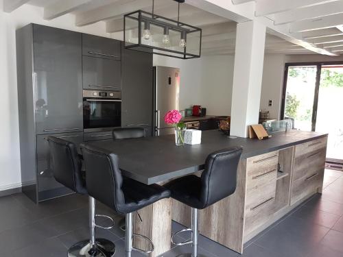 une cuisine avec une table noire et des chaises noires dans l'établissement Longère La Grange, à Andrivaux