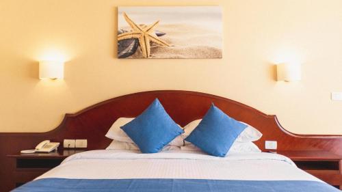 a bed with blue pillows in a hotel room at Labranda Royal Makadi in Hurghada