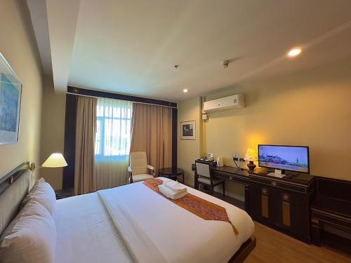 a hotel room with a bed and a desk and a television at Wangchan Riverview in Phitsanulok