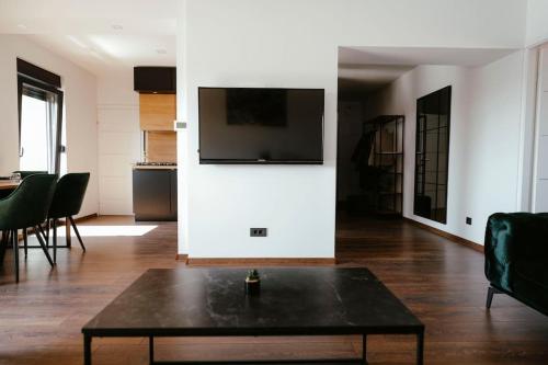 ein Wohnzimmer mit einem Tisch und einem TV an der Wand in der Unterkunft Apartman Marinela in Belišće