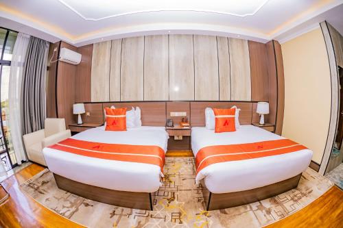 a hotel room with two beds with orange pillows at M Hotel Kigali in Kigali
