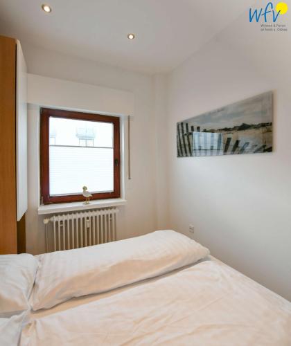a white bedroom with a bed and a window at Dünenschlösschen Ferienwohnung 45 in Wangerooge