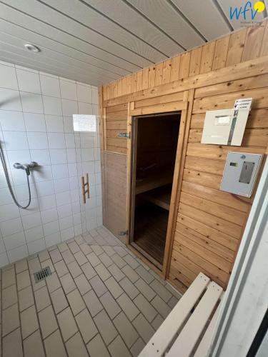 a bathroom with a shower with a wooden wall at Dünenschlösschen Ferienwohnung 45 in Wangerooge