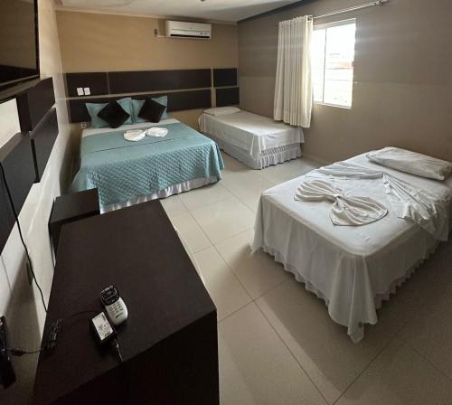 ein Hotelzimmer mit 2 Betten und einem Tisch in der Unterkunft Serra's Palace Hotel in Parauapebas