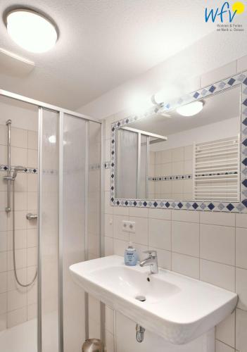 a bathroom with a sink and a shower and a mirror at Villa Cila Ferienwohnung 5 in Wangerooge