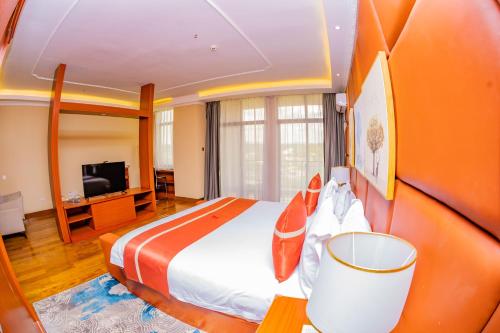 a hotel room with a bed and a television at M Hotel Kigali in Kigali