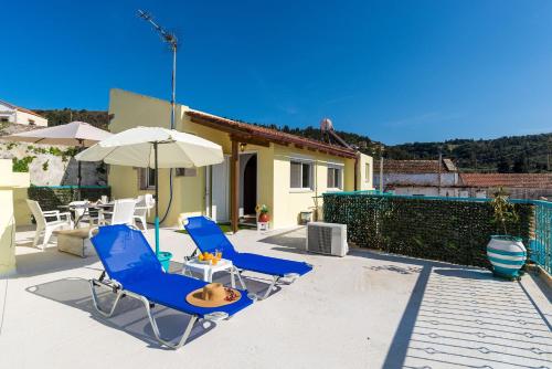 a patio with two blue chairs and an umbrella at Andreas Guest House in Gavalochori