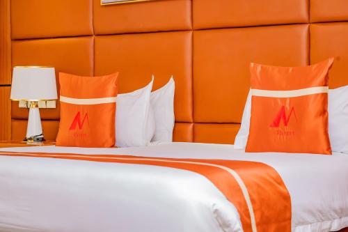 a bedroom with a bed with orange pillows at M Hotel Kigali in Kigali