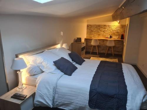 um quarto com uma grande cama branca com almofadas azuis em La casa cosy love, avec jacuzzi et sauna privés em Palau-del-Vidre