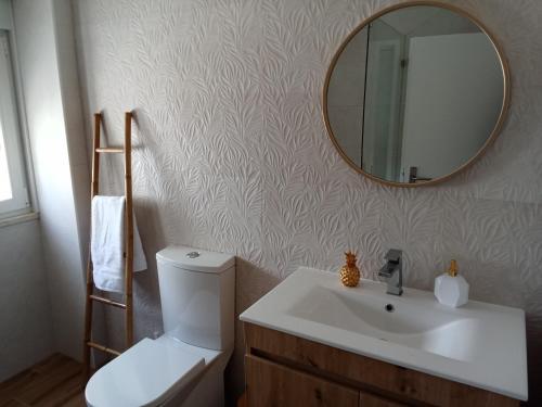 a bathroom with a toilet and a sink and a mirror at Casa Raios de Sol in Burgau