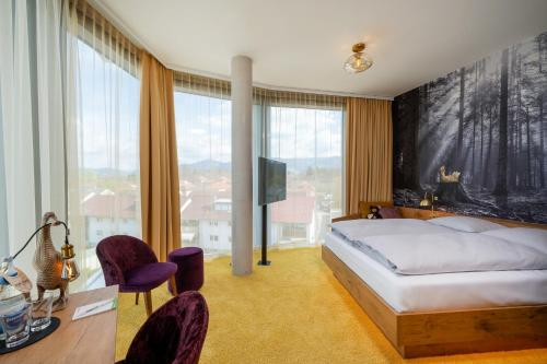 a bedroom with a bed and a tv and some windows at mightyTwice Hotel Achern in Achern