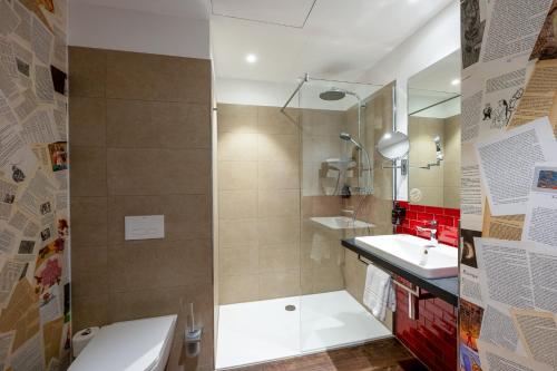a bathroom with a shower and a toilet and a sink at mightyTwice Hotel Achern in Achern
