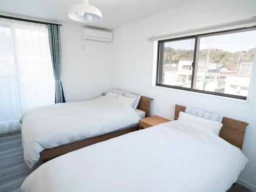 Duas camas num quarto com uma janela em GLOCE長谷 QRPハウスKAMAKURA em Kamakura