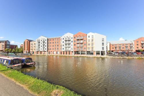 a river with two boats in front of buildings at For Students Only - The Towpath in Chester in Chester