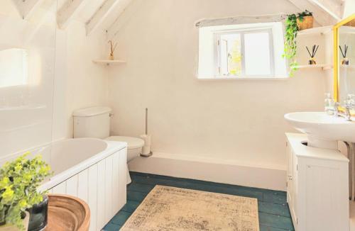 La salle de bains est pourvue d'une baignoire, d'un lavabo et de toilettes. dans l'établissement Inglenook Cottage, The Cotswolds, à Winchcombe