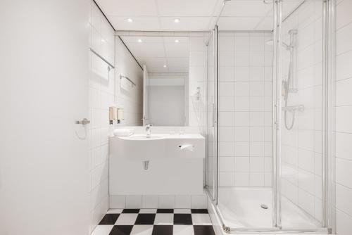 een witte badkamer met een wastafel en een douche bij City Hotel Hengelo in Hengelo