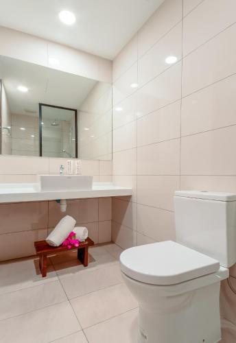 a white bathroom with a toilet and a sink at Ranthari Hotel and Spa Ukulhas Maldives in Ukulhas
