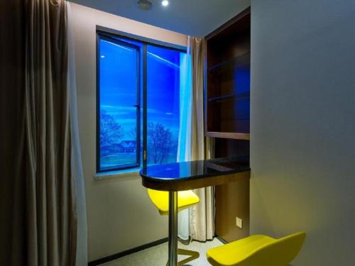 a room with a table and a window with a yellow chair at Zmax Qingyuan Guangqing Railway Station in Qingyuan