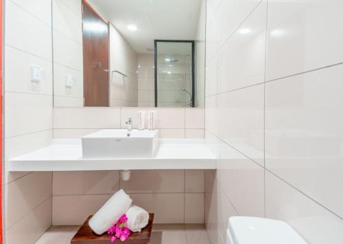 a white bathroom with a sink and a mirror at Ranthari Hotel and Spa Ukulhas Maldives in Ukulhas