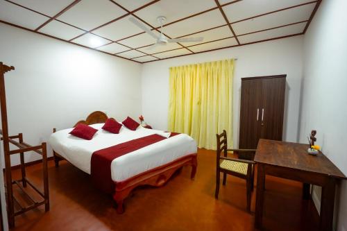 a bedroom with a bed and a table and a desk at Sawani Home in Ambalangoda